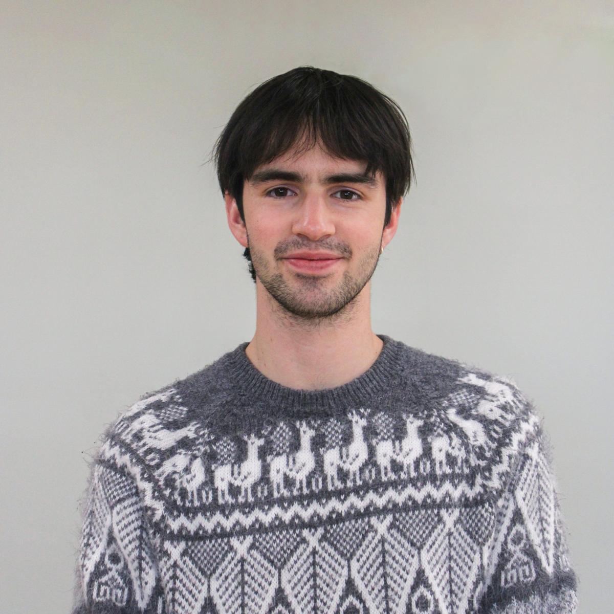 Young man smiling against a white light background.