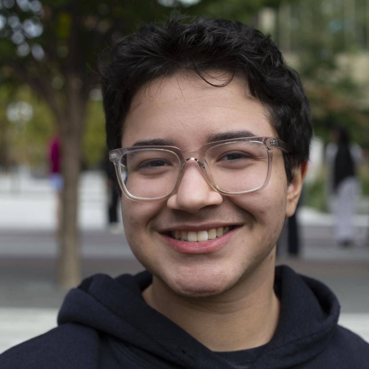 Smiling young person wearing glasses against a blurred background.