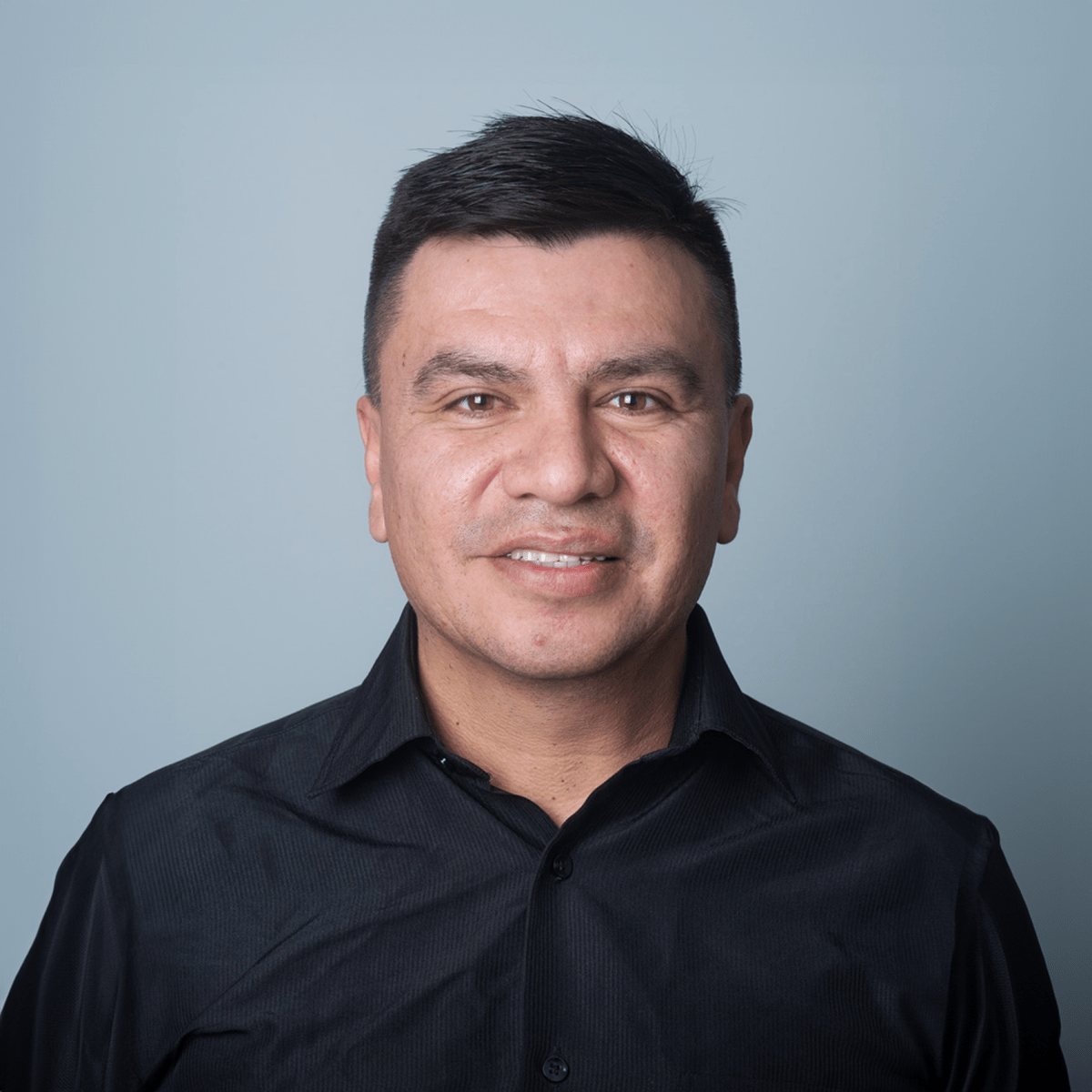 Portrait of man in black shirt smiling.